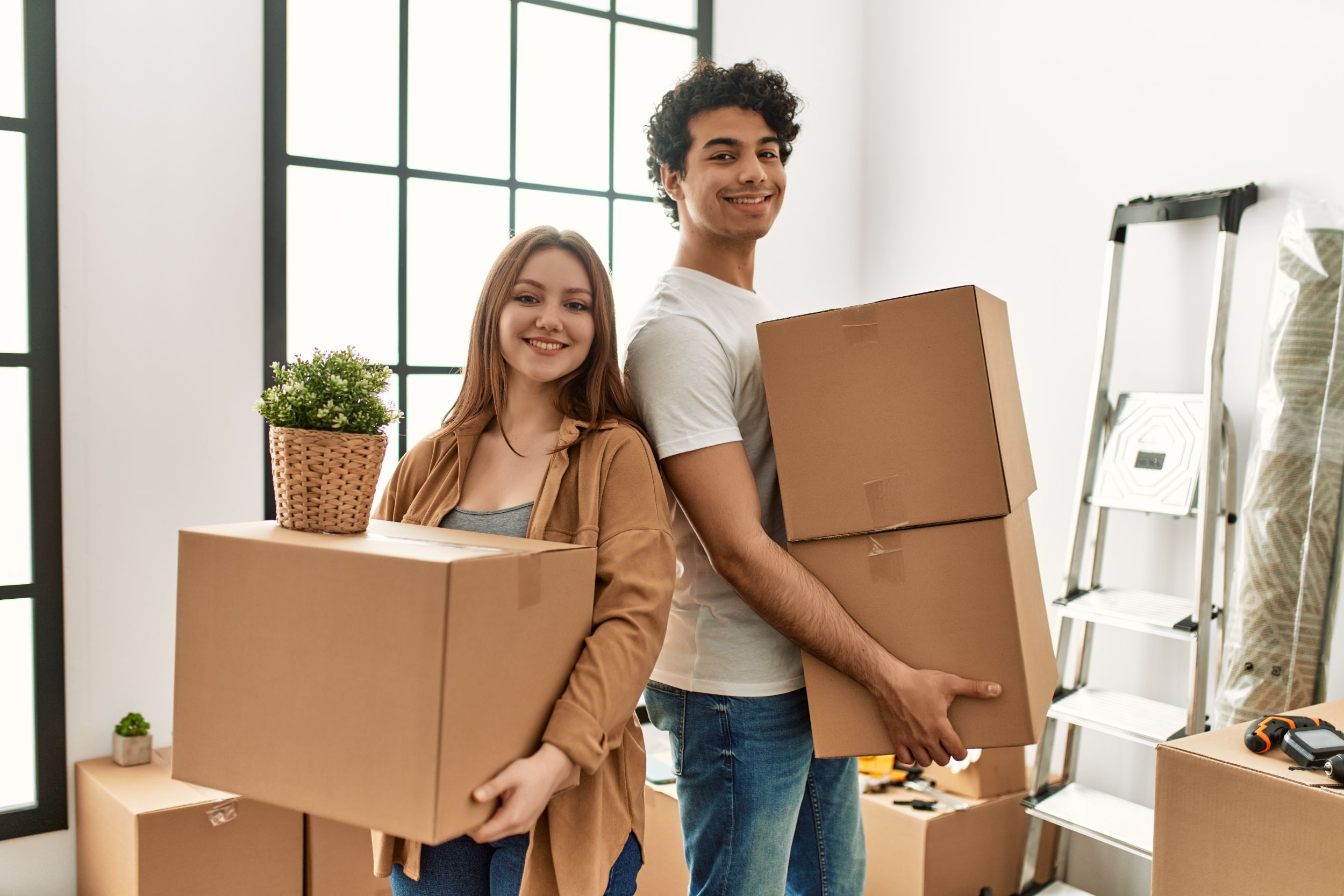 Young couple smiling happy holding cardboard boxes at new home